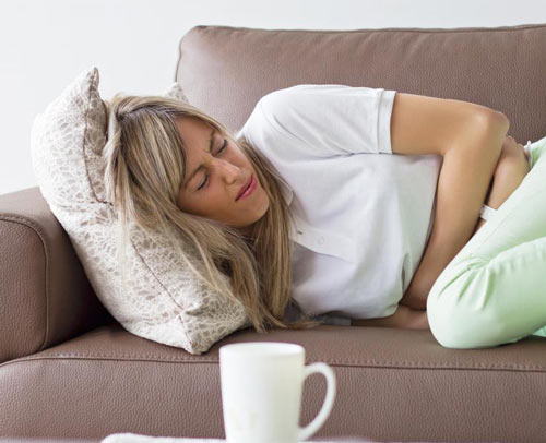 woman-in-green-pants-in-chair-with-stomach-pain